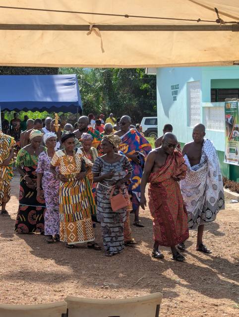 Elders and women arrive in procession at the school grounds.