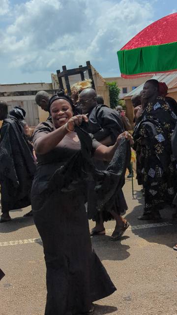 A woman in black smiles as she dances along the route.