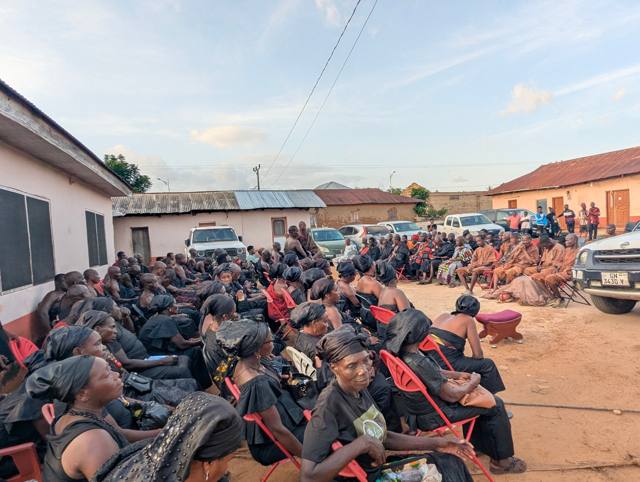 Members of the Asafo group, in brown attire, seated among the gathering.