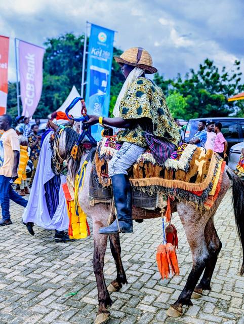 A rider on a decorated horse passes festival banners.