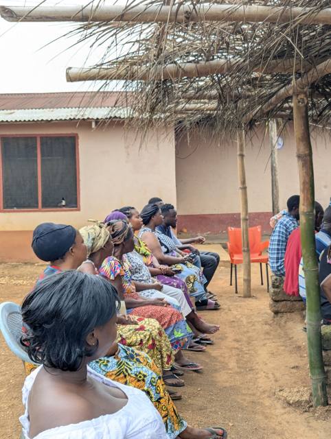 Members of the Fodome Amele community gathered under a traditional shelter.