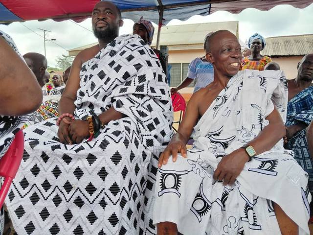 Two elders seated side by side in black-and-white patterned cloth.