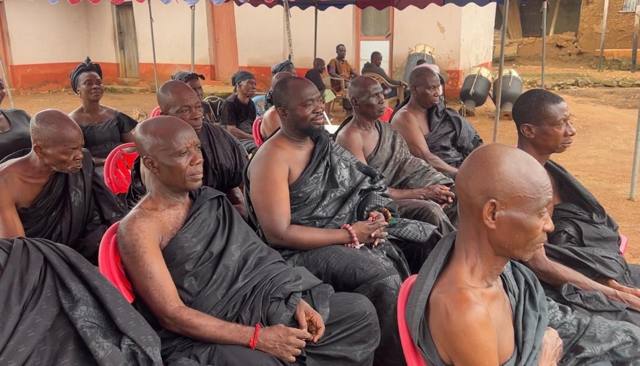 Elders in black cloth seated together.