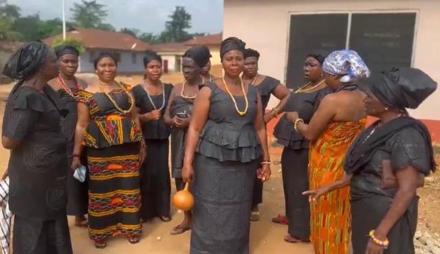 Women in black and coloured cloth standing together in the compound.